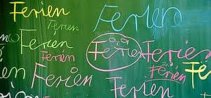 grüne Kreidetafel auf der mehrmals das Wort Ferien geschrieben steht