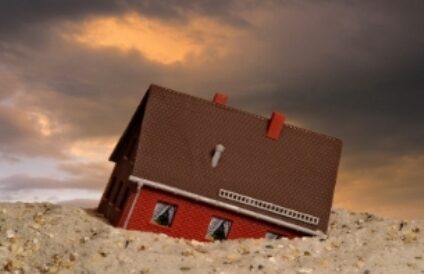 Auf dem Bild versinkt ein Haus im Sand.