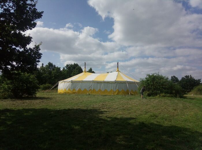 Gelb-weißes großes Zelt auf Wiese